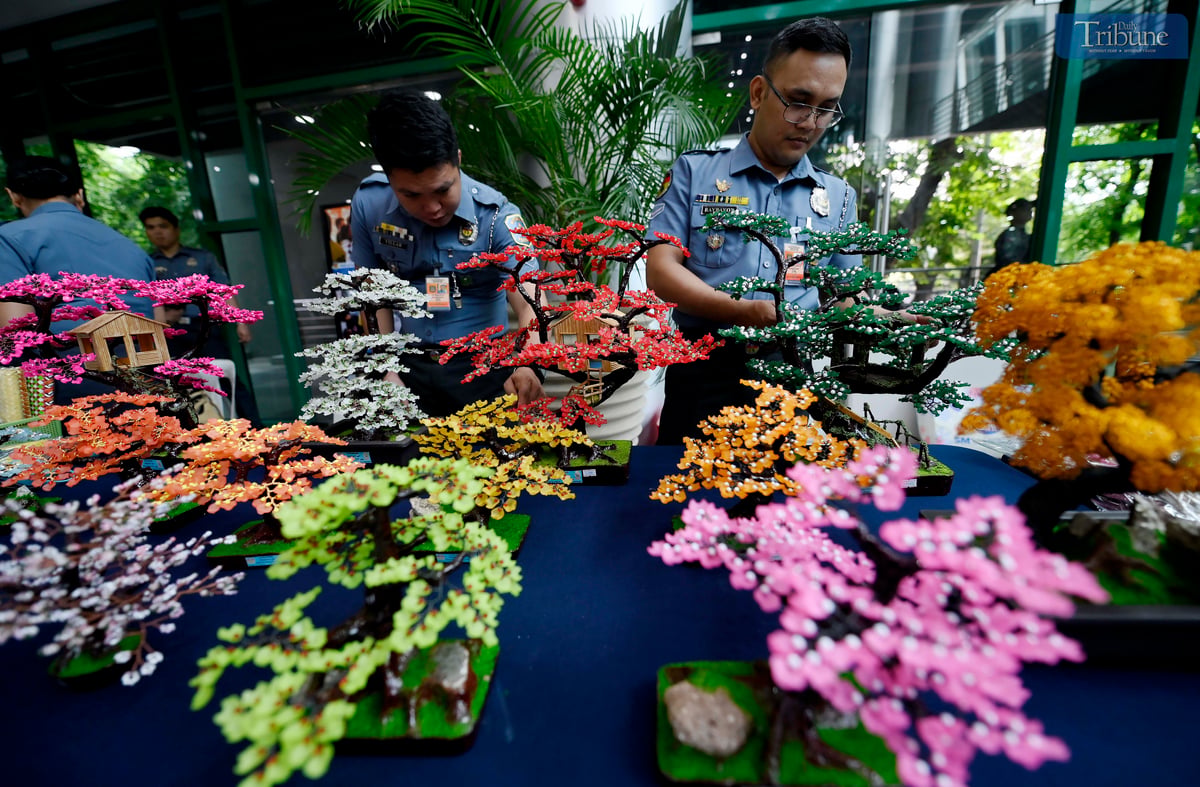 Bureau of Jail Management and Penology (BJMP) personnel arrange handcrafted wire-beaded bonsai trees made by persons deprived of liberty (PDLs) for sale during the agency’s 34th anniversary celebration on Wednesday, July 2, 2025. Proceeds from the decorative pieces support PDL artists and their families.