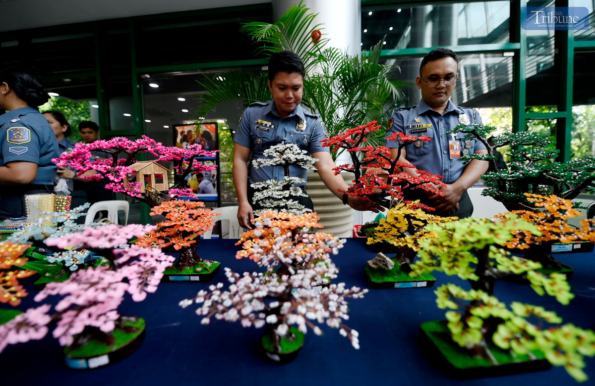 Bureau of Jail Management and Penology (BJMP) personnel arrange handcrafted wire-beaded bonsai trees made by persons deprived of liberty (PDLs) for sale during the agency’s 34th anniversary celebration on Wednesday, July 2, 2025. Proceeds from the decorative pieces support PDL artists and their families.