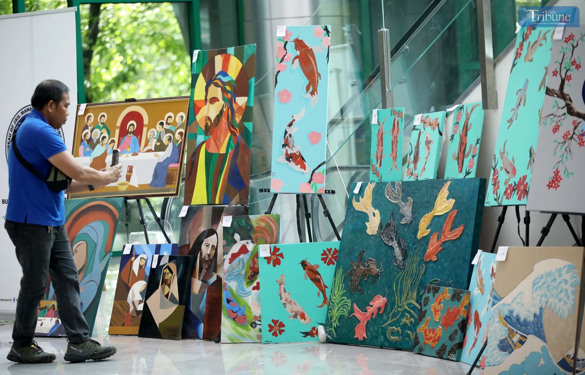 A man photographs a painting made by a person deprived of liberty (PDL), displayed at the M.I.C.E. Building in Quezon City Hall on Wednesday, July 2, 2025. The artwork, showcased during the Bureau of Jail Management and Penology’s (BJMP) 34th anniversary celebration, is being sold to raise funds for PDL artists and their families.