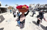 PALESTINIANS move with their belongings following Israeli evacuation orders for Khan Yunis on 19 May. Israel said it will “take control” of the whole of Gaza, where rescuers reported more than 50 killed in Israeli strikes as the military pressed a newly intensified campaign.