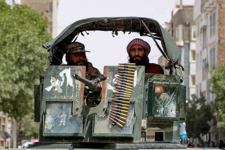 Armed Taliban security personnel sit atop a humvee armored vehicle as they keep guard during a religious procession by Afghan Shiite Muslims celebrating Ashura, on the tenth day of the Islamic holy month of Muharram, in Herat on July 6, 2025.