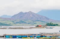 TAAL Volcano looms in the background as the Philippine Coast Guard conducts search and recovery operations off Laurel, Batangas — where the remains of the missing sabungeros were allegedly dumped. A tarped banca and an ROV assist divers facing poor visibility and harsh underwater conditions.