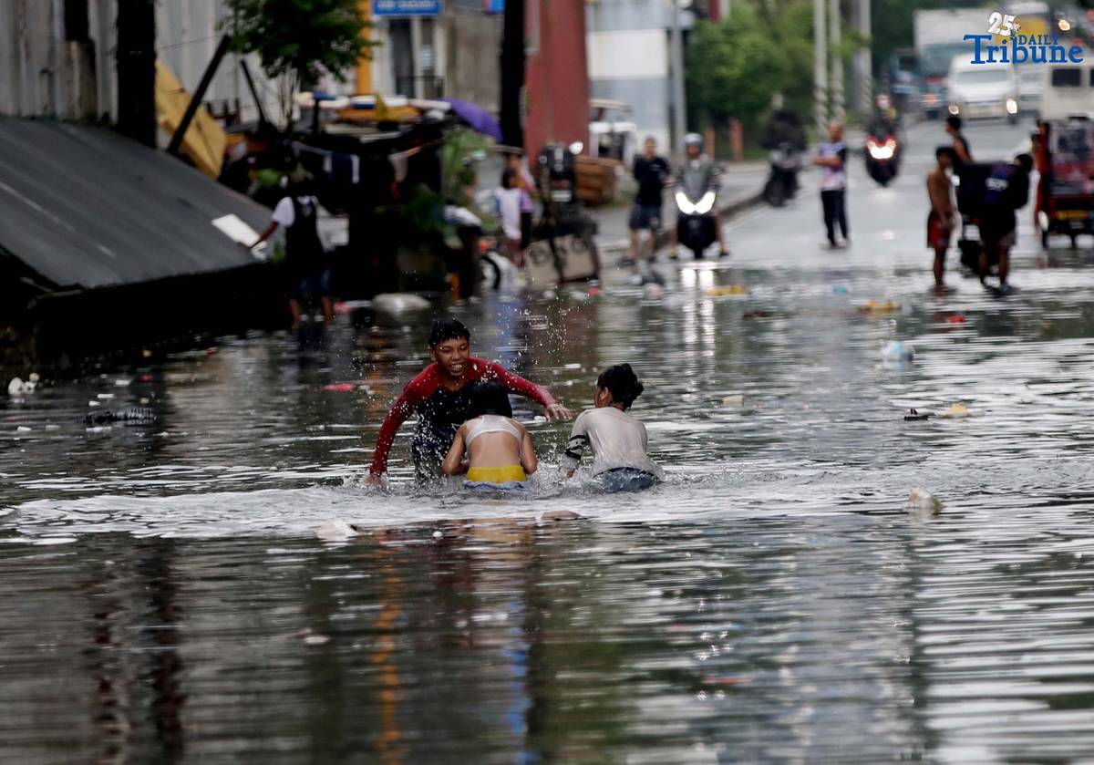 Children bathe and play in waist-deep floodwaters along Maria Clara Street in Quezon City on Saturday, 19 July 2025, following continuous rains from the Habagat, intensified by Severe Tropical Storm Crising.