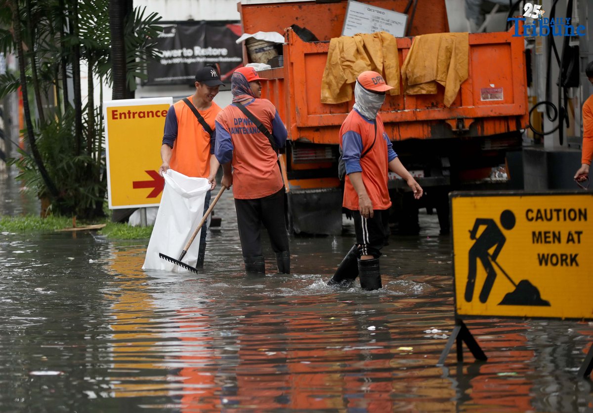 Department of Public Works and Highways (DPWH) personnel collect garbage washed up by floodwaters along Araneta Avenue in Quezon City on Saturday, 19 July 2025, following heavy rainfall.