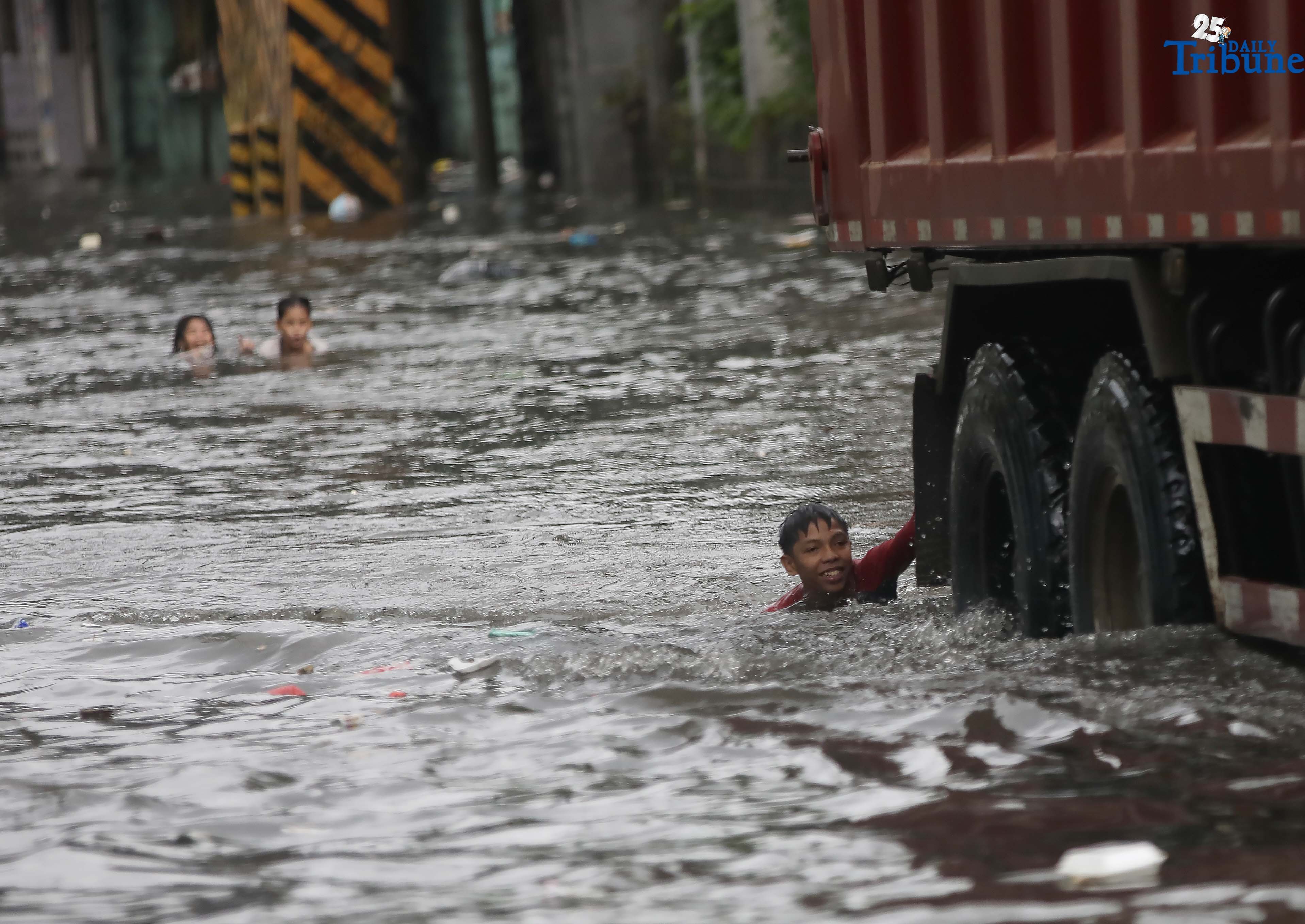 Children play in floodwaters in Quezon City