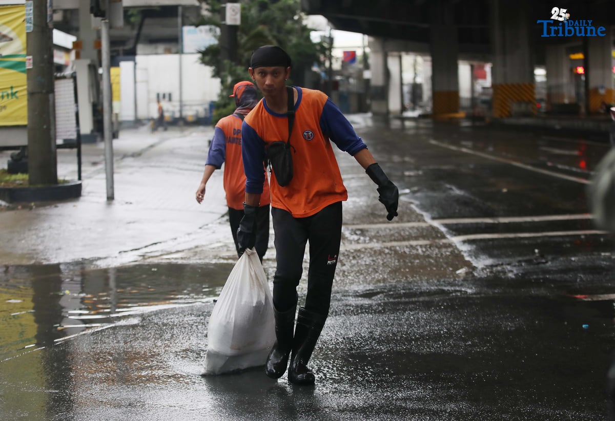 Department of Public Works and Highways (DPWH) personnel collect garbage washed up by floodwaters along Araneta Avenue in Quezon City on Saturday, 19 July 2025, following heavy rainfall.