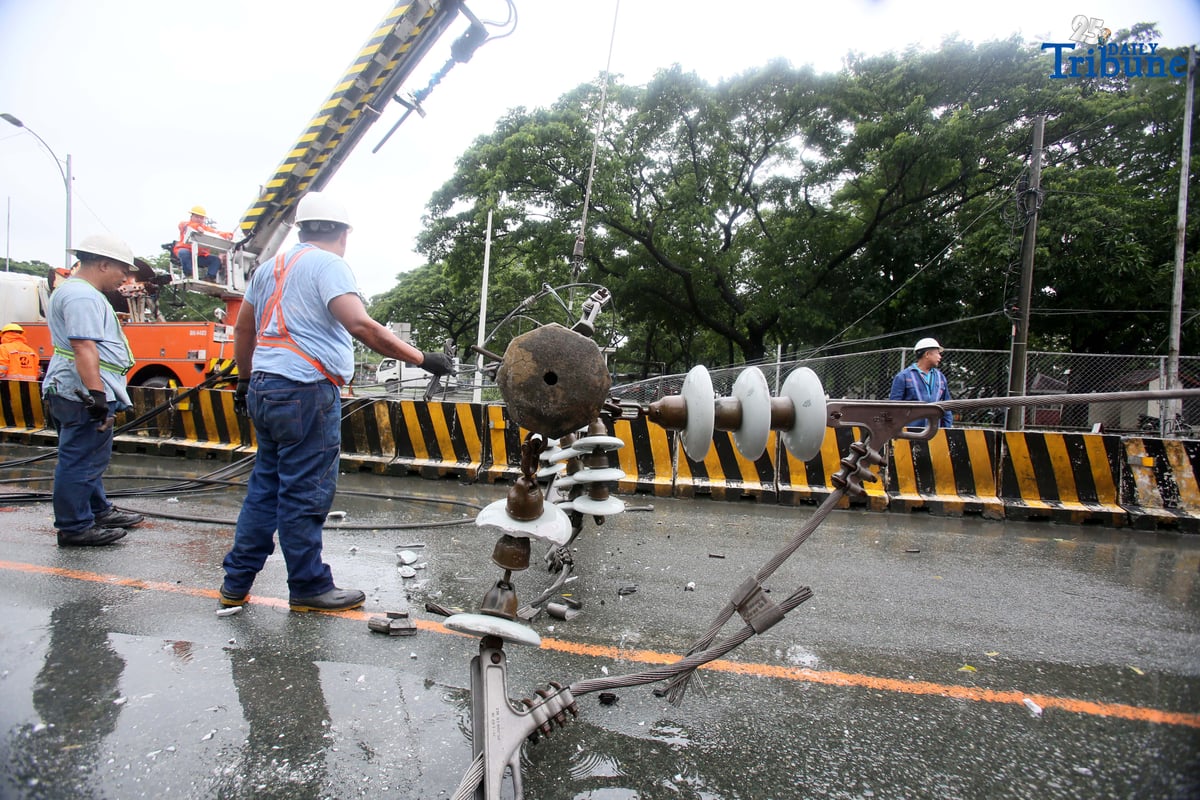 Personnel from Meralco, MMDA, and the Quezon City Police District work together to remove a fallen electric post along the northbound lane of Katipunan Avenue in Quezon City on Saturday, July 19, 2025. The post was knocked down by strong winds brought by the Habagat, intensified by Severe Tropical Storm Crising, around 11 a.m. Two vehicles reportedly crashed due to the incident.