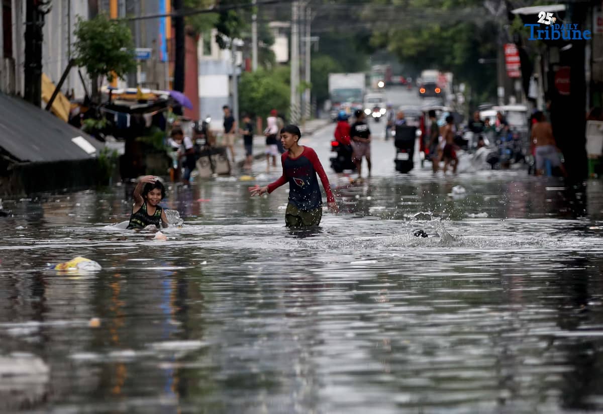 Children bathe and play in waist-deep floodwaters along Maria Clara Street in Quezon City on Saturday, 19 July 2025, following continuous rains from the Habagat, intensified by Severe Tropical Storm Crising.