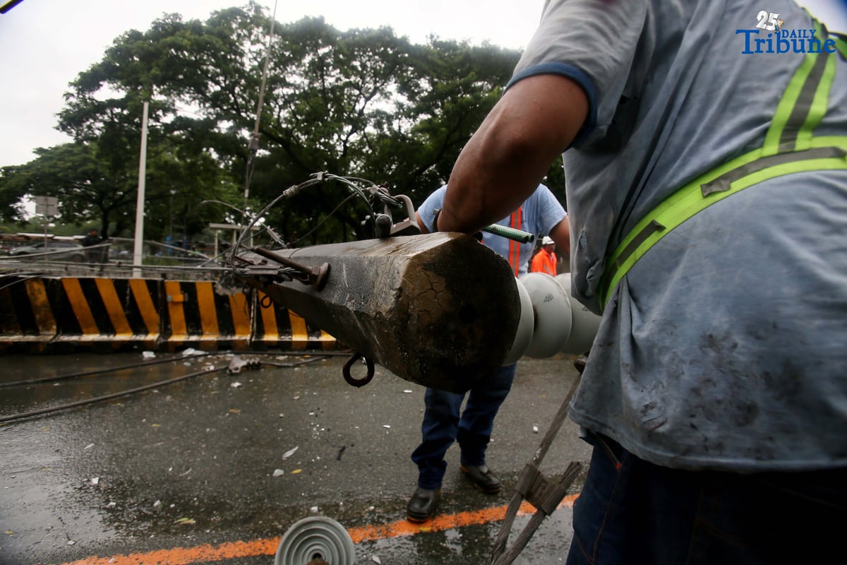 Personnel from Meralco, MMDA, and the Quezon City Police District work together to remove a fallen electric post along the northbound lane of Katipunan Avenue in Quezon City on Saturday, July 19, 2025. The post was knocked down by strong winds brought by the Habagat, intensified by Severe Tropical Storm Crising, around 11 a.m. Two vehicles reportedly crashed due to the incident.