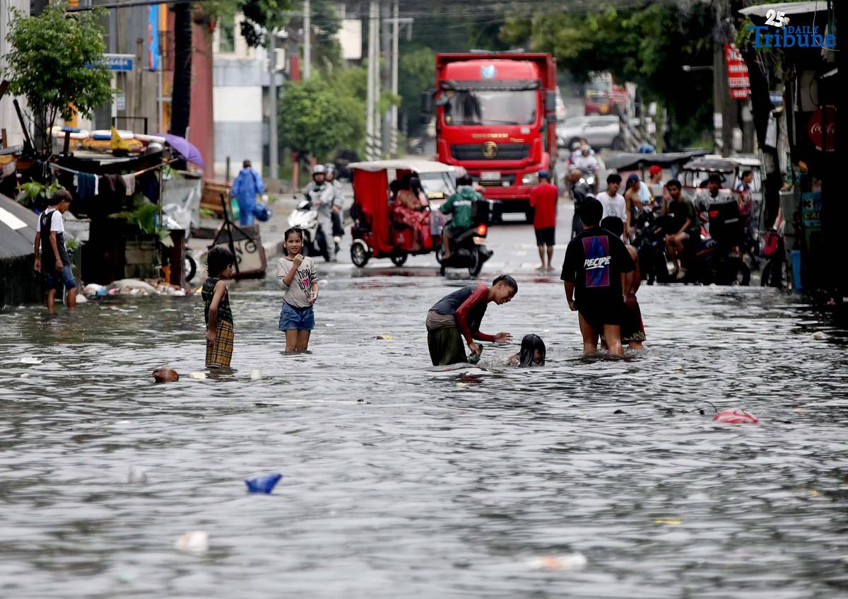 Children bathe and play in waist-deep floodwaters along Maria Clara Street in Quezon City on Saturday, 19 July 2025, following continuous rains from the Habagat, intensified by Severe Tropical Storm Crising.
