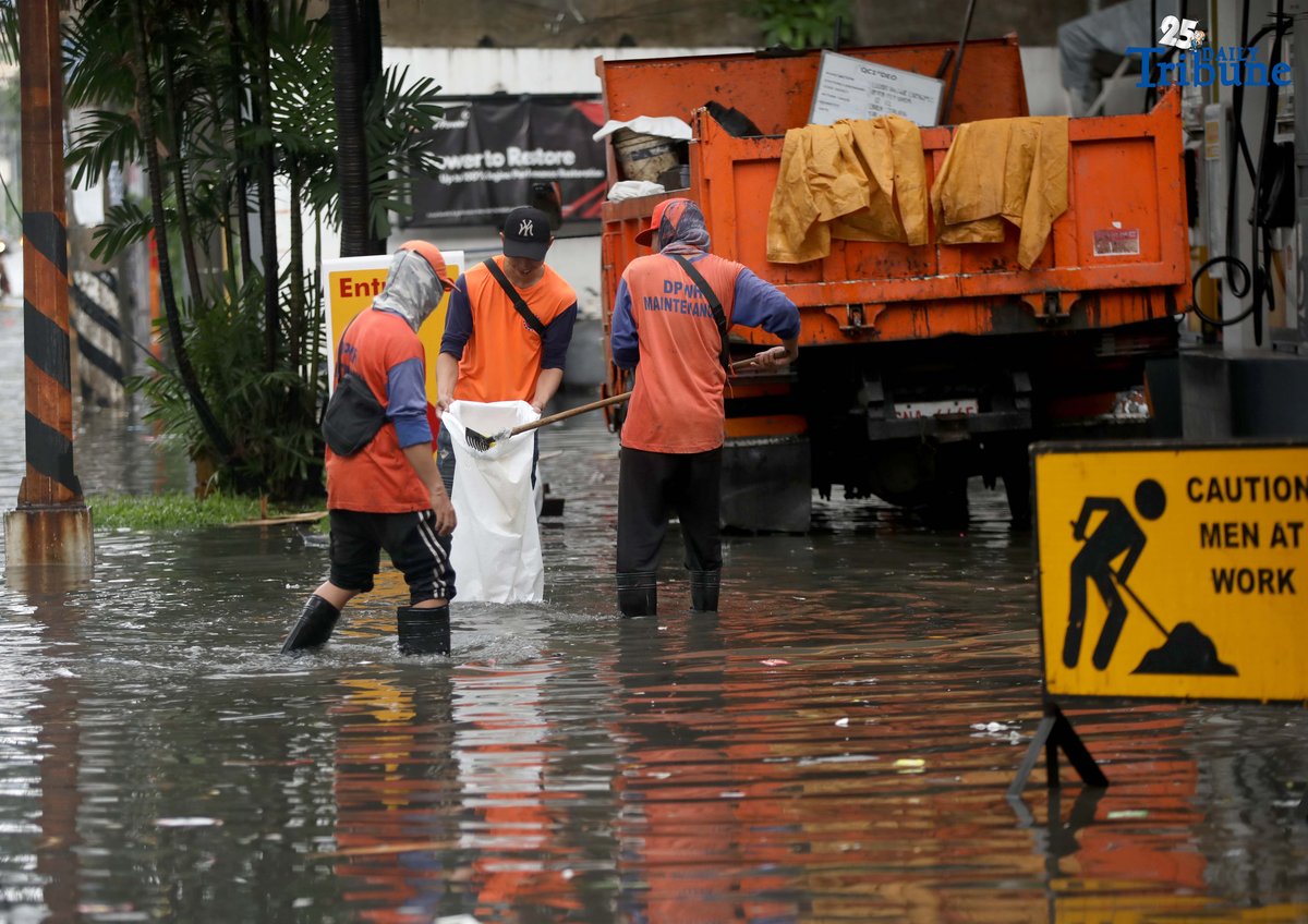 Department of Public Works and Highways (DPWH) personnel collect garbage washed up by floodwaters along Araneta Avenue in Quezon City on Saturday, 19 July 2025, following heavy rainfall.