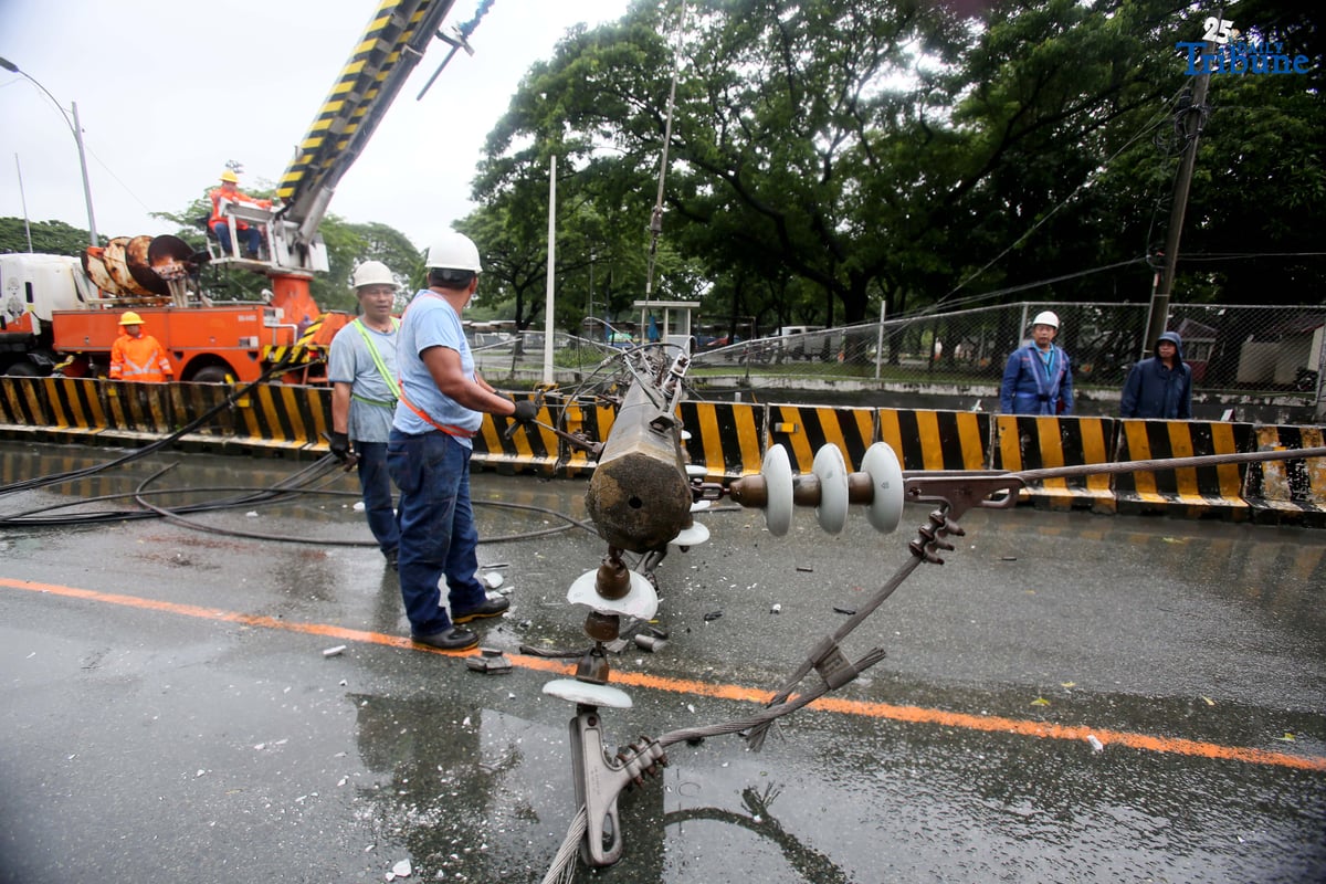Personnel from Meralco, MMDA, and the Quezon City Police District work together to remove a fallen electric post along the northbound lane of Katipunan Avenue in Quezon City on Saturday, July 19, 2025. The post was knocked down by strong winds brought by the Habagat, intensified by Severe Tropical Storm Crising, around 11 a.m. Two vehicles reportedly crashed due to the incident.
