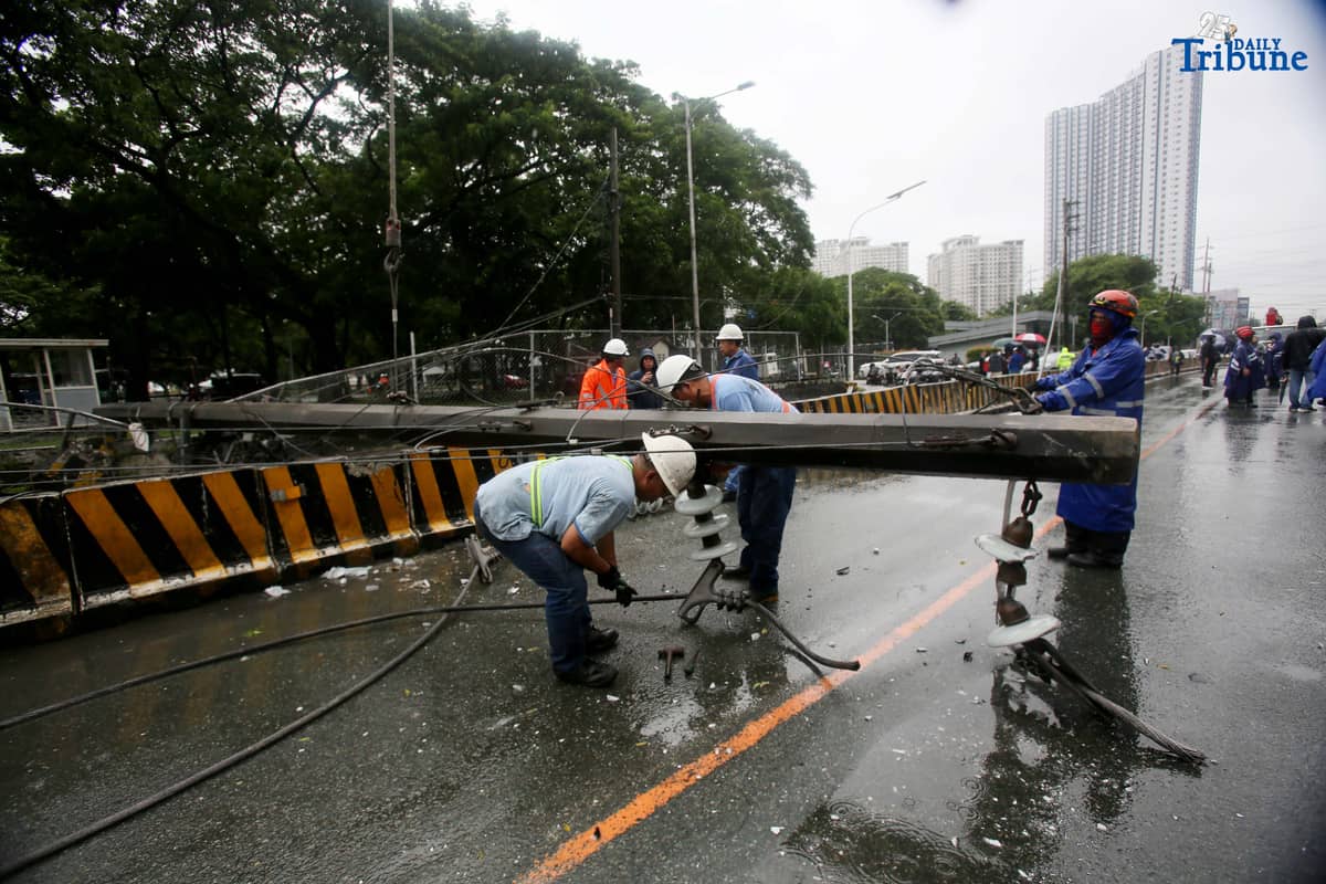 Personnel from Meralco, MMDA, and the Quezon City Police District work together to remove a fallen electric post along the northbound lane of Katipunan Avenue in Quezon City on Saturday, July 19, 2025. The post was knocked down by strong winds brought by the Habagat, intensified by Severe Tropical Storm Crising, around 11 a.m. Two vehicles reportedly crashed due to the incident.