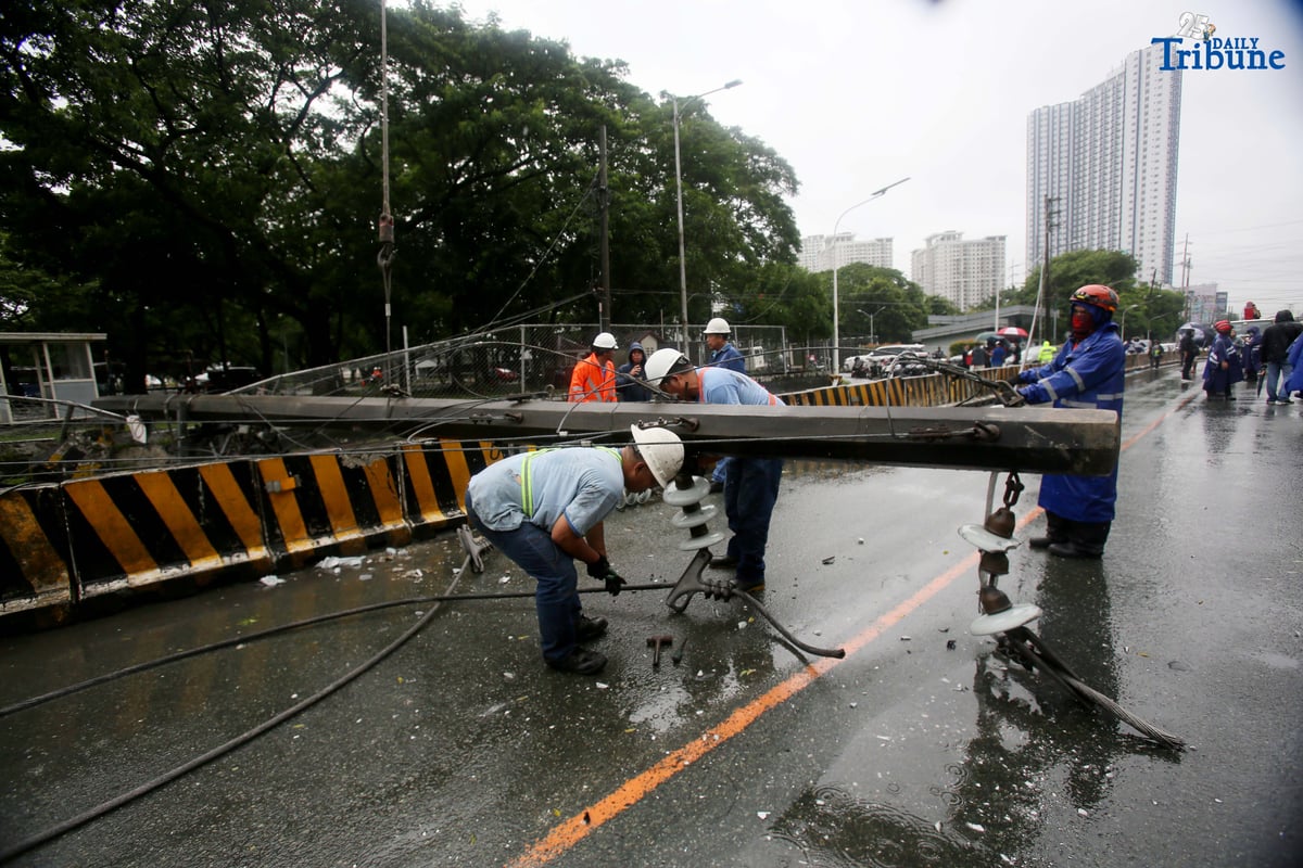 Personnel from Meralco, MMDA, and the Quezon City Police District work together to remove a fallen electric post along the northbound lane of Katipunan Avenue in Quezon City on Saturday, July 19, 2025. The post was knocked down by strong winds brought by the Habagat, intensified by Severe Tropical Storm Crising, around 11 a.m. Two vehicles reportedly crashed due to the incident.