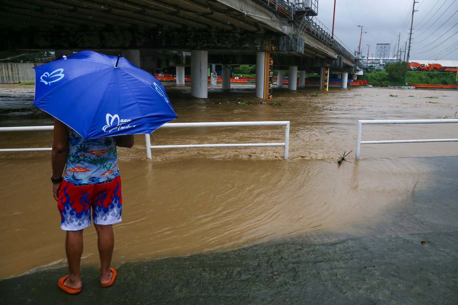 Residents monitor the water level of the Marikina River as it hits the second alarm at 3:00 in the afternoon of 21 July 2025 due to heavy rains brought by Habagat.