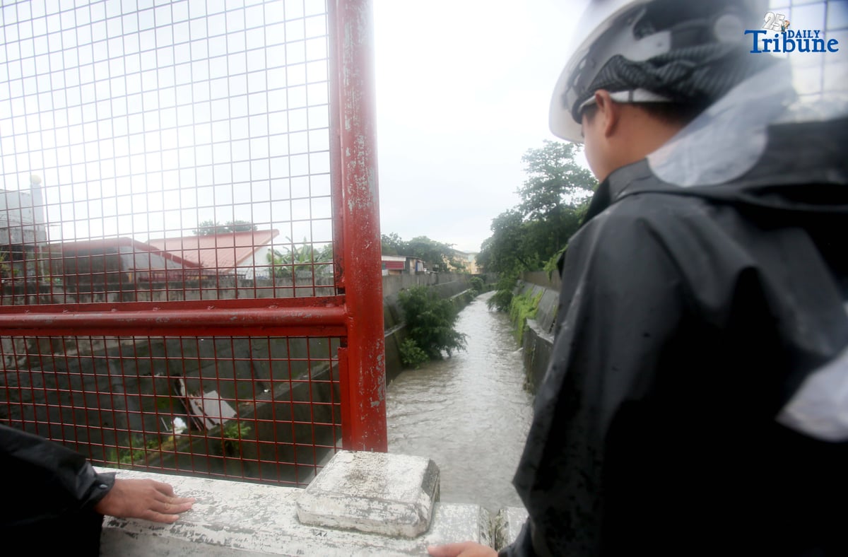 Personnel from La Mesa Dam monitor the water level at Tullahan River in Quezon City on Monday, July 21, 2025, after the dam overflowed due to heavy rains. The water level reached 80.16 meters, breaching its spilling threshold of 80.15 meters.