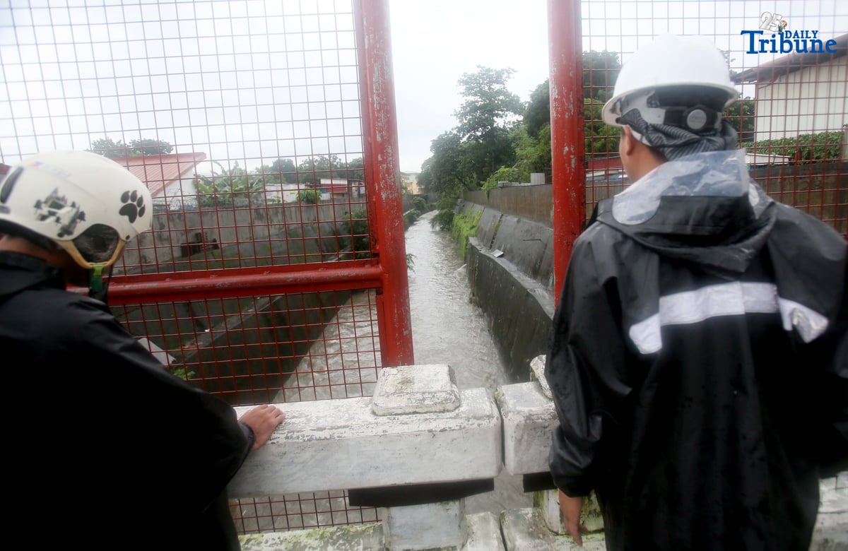 Personnel from La Mesa Dam monitor the water level at Tullahan River in Quezon City on Monday, July 21, 2025, after the dam overflowed due to heavy rains. The water level reached 80.16 meters, breaching its spilling threshold of 80.15 meters.