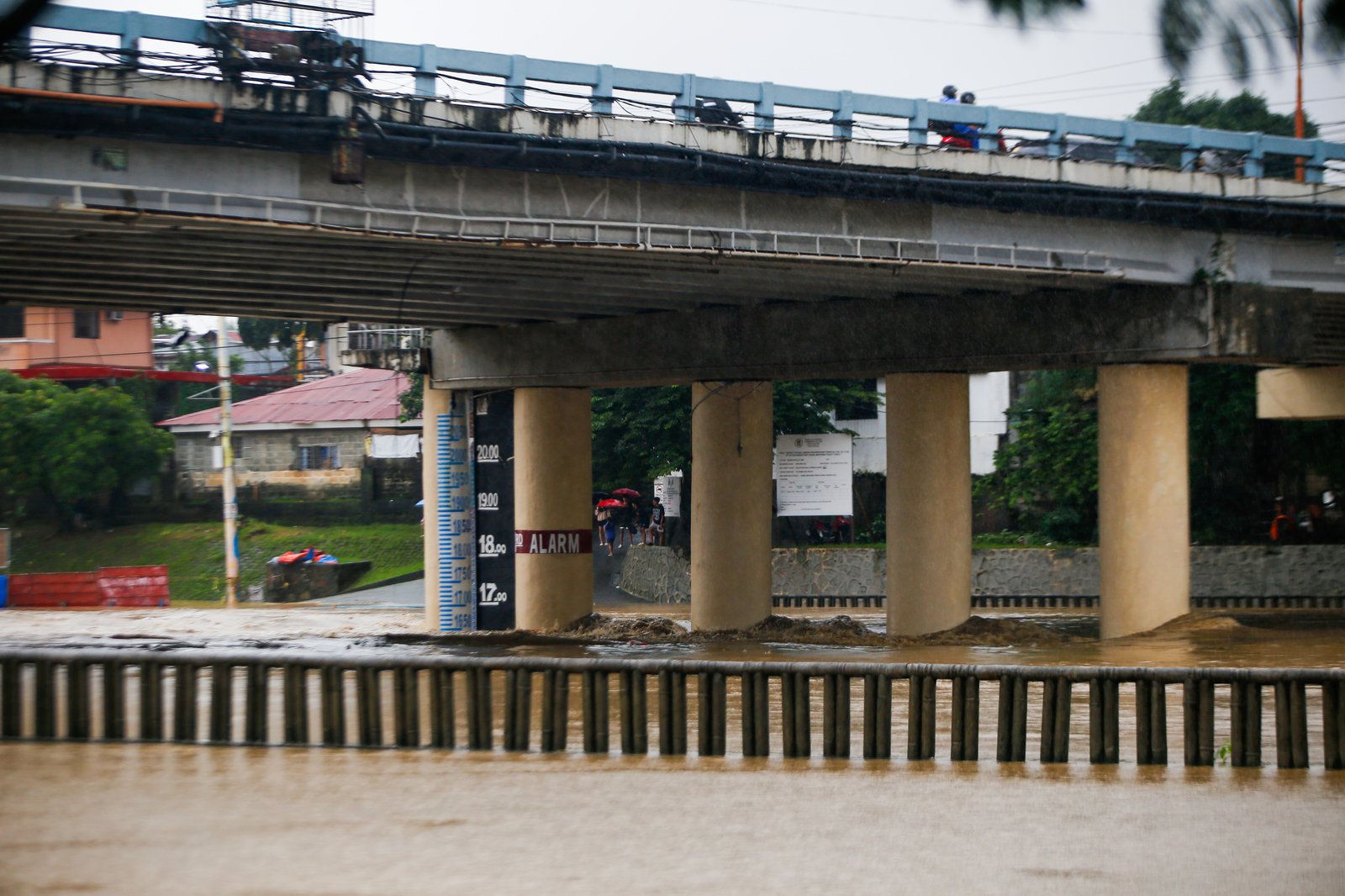 Residents monitor the water level of the Marikina River as it hits the second alarm at 3:00 in the afternoon of 21 July 2025 due to heavy rains brought by Habagat.