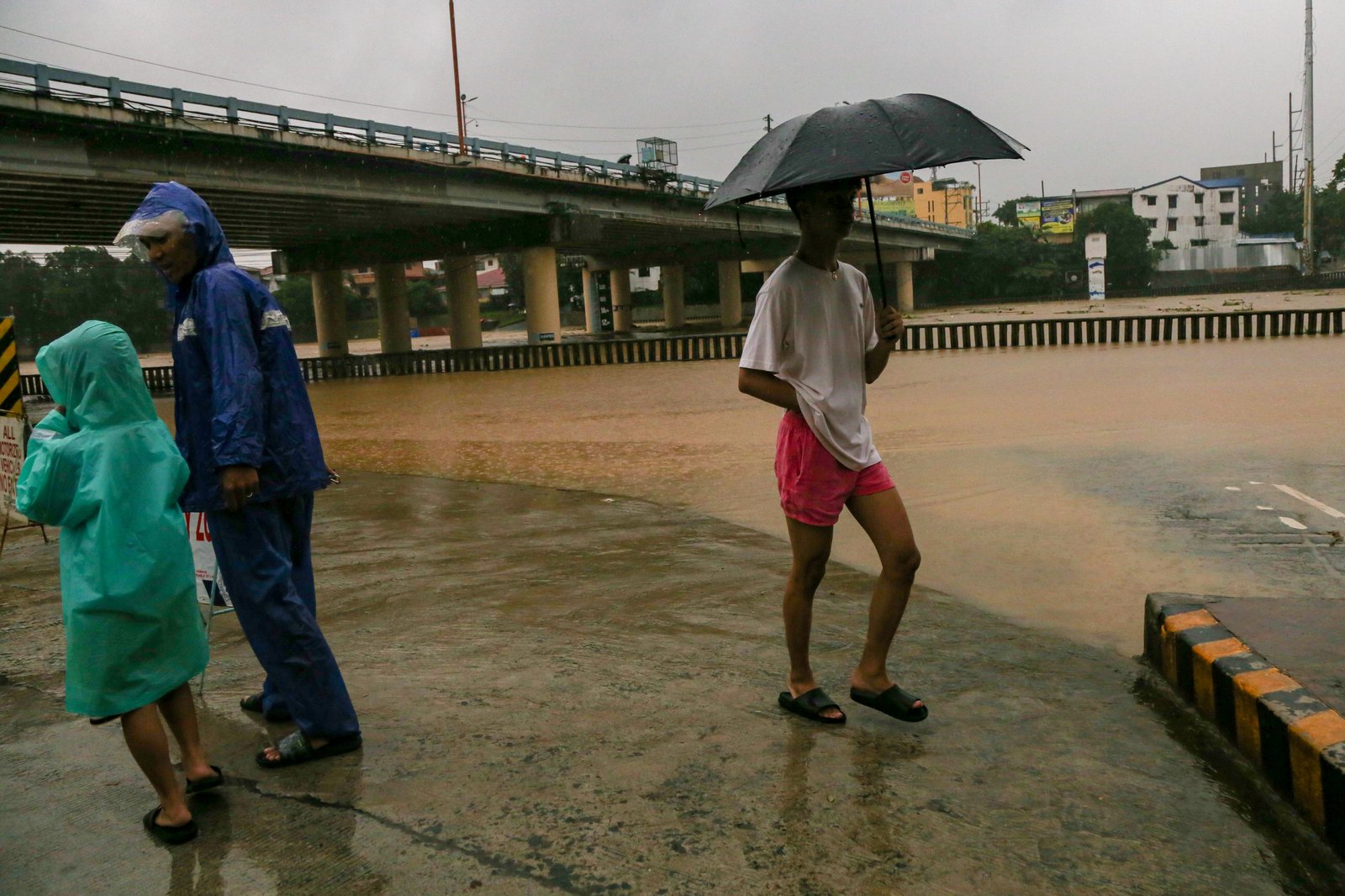 Residents monitor the water level of the Marikina River as it hits the second alarm at 3:00 in the afternoon of 21 July 2025 due to heavy rains brought by Habagat.