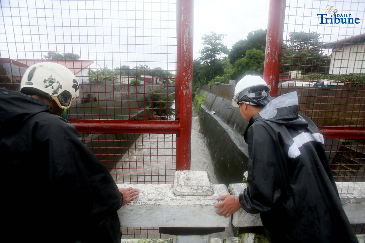 Personnel from La Mesa Dam monitor the water level at Tullahan River in Quezon City on Monday, July 21, 2025, after the dam overflowed due to heavy rains. The water level reached 80.16 meters, breaching its spilling threshold of 80.15 meters.
