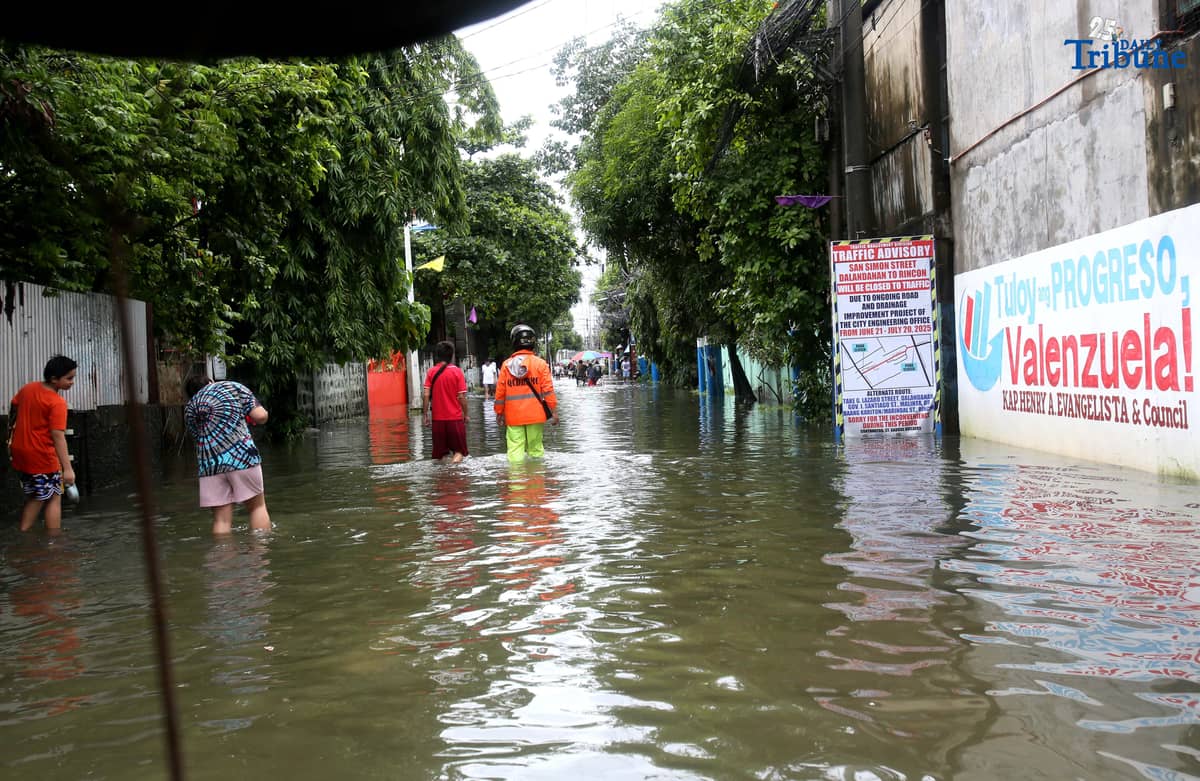 Residents in Barangay Rincon, Valenzuela City wade through flooded roads on July 22, 2025, as continuous rains submerge parts of the area. The southwest monsoon, or habagat, is expected to bring more moderate to heavy rainfall across Metro Manila, Luzon, and parts of the Visayas over the next three days, according to PAGASA.