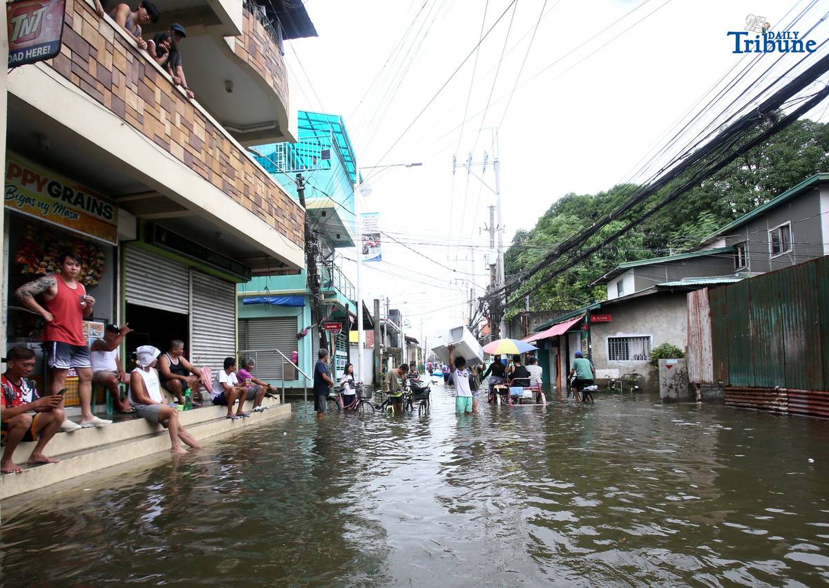 Residents in Barangay Rincon, Valenzuela City wade through flooded roads on July 22, 2025, as continuous rains submerge parts of the area. The southwest monsoon, or habagat, is expected to bring more moderate to heavy rainfall across Metro Manila, Luzon, and parts of the Visayas over the next three days, according to PAGASA.