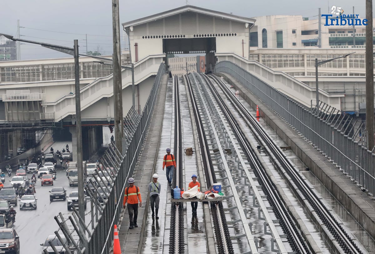 MRT-7 workers walk along the train tracks near Batasan Station on Commonwealth Avenue, Quezon City, on Wednesday, July 23, 2025. The 22-kilometer elevated railway project—connecting Metro Manila and Bulacan through 14 stations—is now 83.08% complete. Trial runs are expected to begin by the end of 2025, with full operations targeted for 2026 and a projected daily ridership of 600,000.