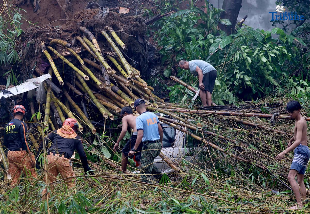 Rescuers from the Bureau of Fire Protection, Quezon City Police District, and the Quezon City local government remove toppled bamboo trunks that crushed two vehicles after a landslide along Don Vicente Street in Barangay Bagong Silangan, Quezon City, on Wednesday, July 23, 2025.