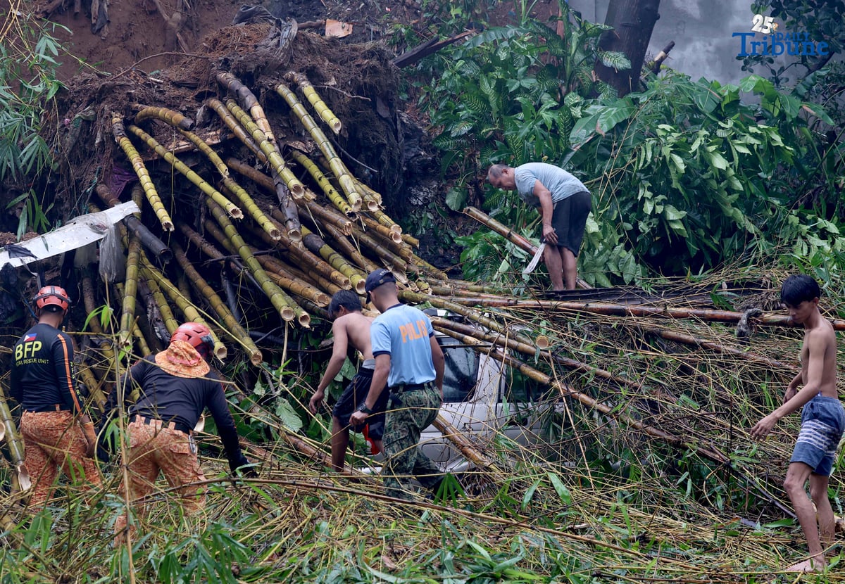 Rescuers from the Bureau of Fire Protection, Quezon City Police District, and the Quezon City local government remove toppled bamboo trunks that crushed two vehicles after a landslide along Don Vicente Street in Barangay Bagong Silangan, Quezon City, on Wednesday, July 23, 2025.