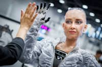 SOPHIE, a robot using artificial intelligence from Hanson Robotics, shares a high five with a visitor during the International Telecommunication Union (ITU) AI for Good Global Summit in Geneva on July 8, 2025.