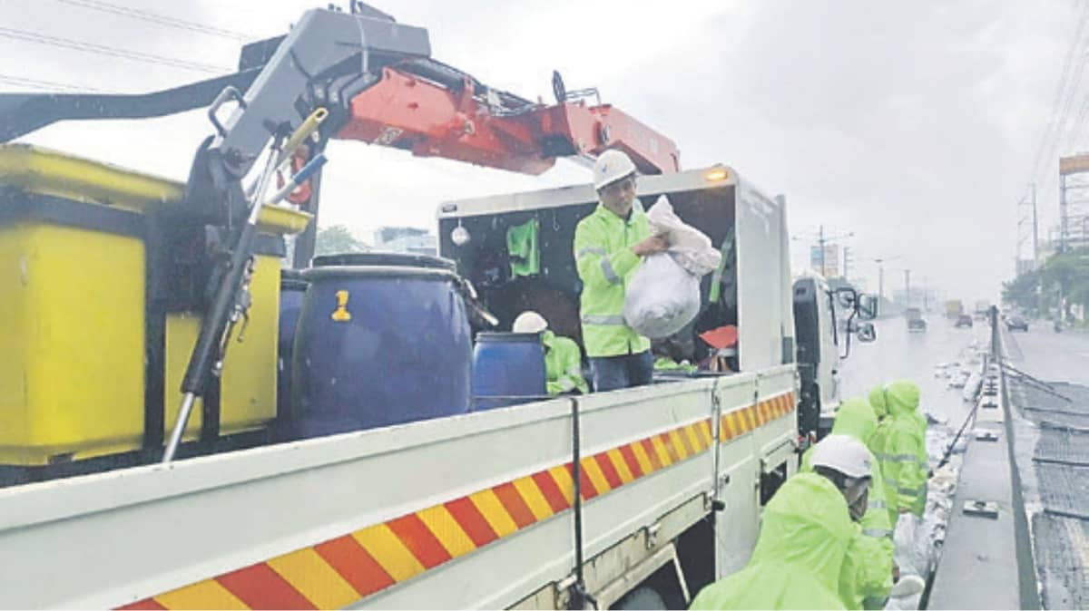 Metro Pacific Tollways Corporation personnel deploy sandbags along
North Luzon Expressway in Valenzuela City as part of flood mitigation
measures amid heavy rains.