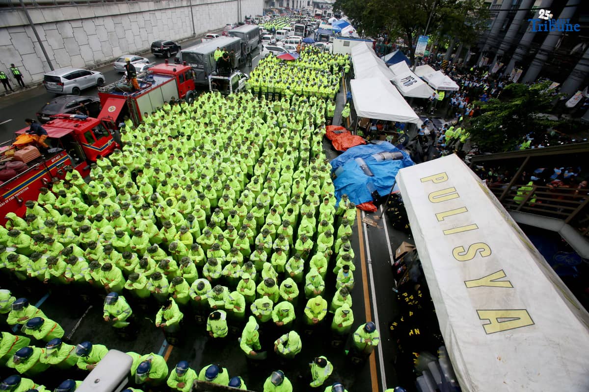 Members of the Philippine National Police (PNP) guard Commonwealth Avenue near St. Peter Church in Quezon City to block militant groups during President Ferdinand Marcos Jr.’s fourth State of the Nation Address.