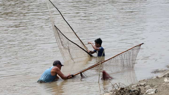 A fisherman uses traditional methods to catch freshwater tilapia at Marikina River Park in Marikina City on Wednesday. After weeks of rainfall, locals turn to fishing as a way to supplement their daily food supply.