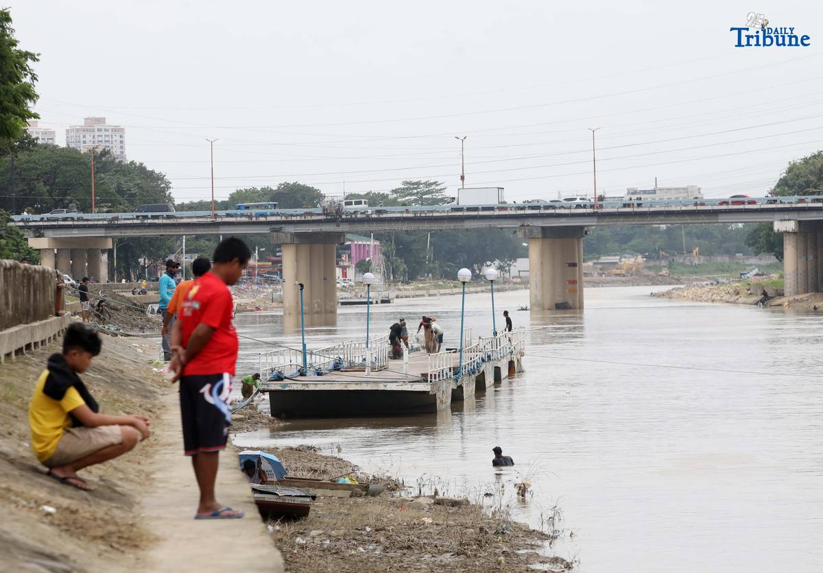 A fisherman uses traditional methods to catch freshwater tilapia at Marikina River Park in Marikina City on Wednesday. After weeks of rainfall, locals turn to fishing as a way to supplement their daily food supply.