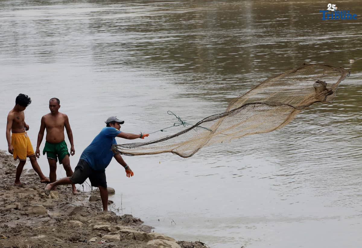A fisherman uses traditional methods to catch freshwater tilapia at Marikina River Park in Marikina City on Wednesday. After weeks of rainfall, locals turn to fishing as a way to supplement their daily food supply.