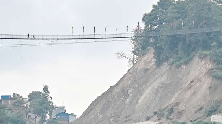 PEOPLE walk across a footbridge at a landslide-prone area near the Arniko Highway in Nepal’s Kavre district.