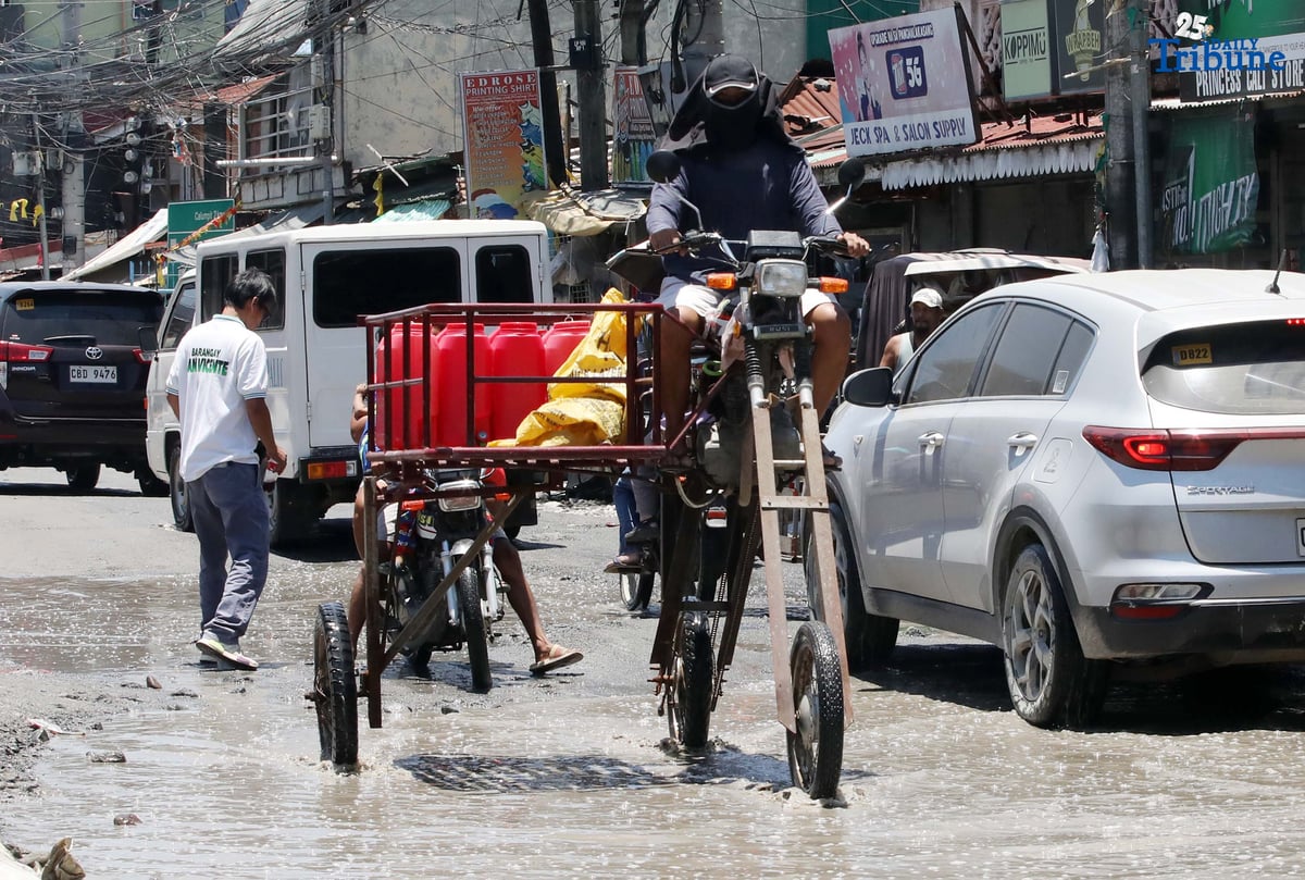An improvised motorbike designed to navigate floods hauls water containers along a submerged portion of Apalit-Macabebe Road in Pampanga on Monday, July 4. Pampanga remains among the provinces most vulnerable to flooding.