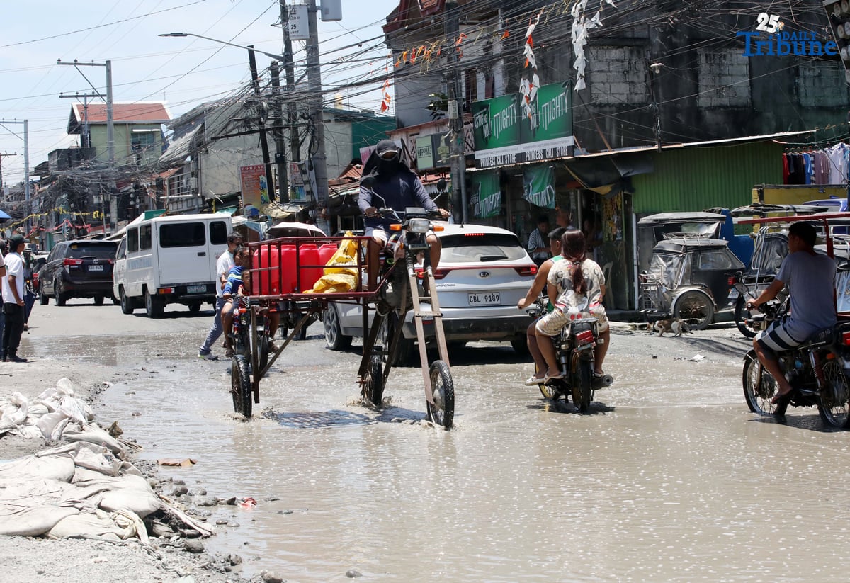 An improvised motorbike designed to navigate floods hauls water containers along a submerged portion of Apalit-Macabebe Road in Pampanga on Monday, July 4. Pampanga remains among the provinces most vulnerable to flooding.