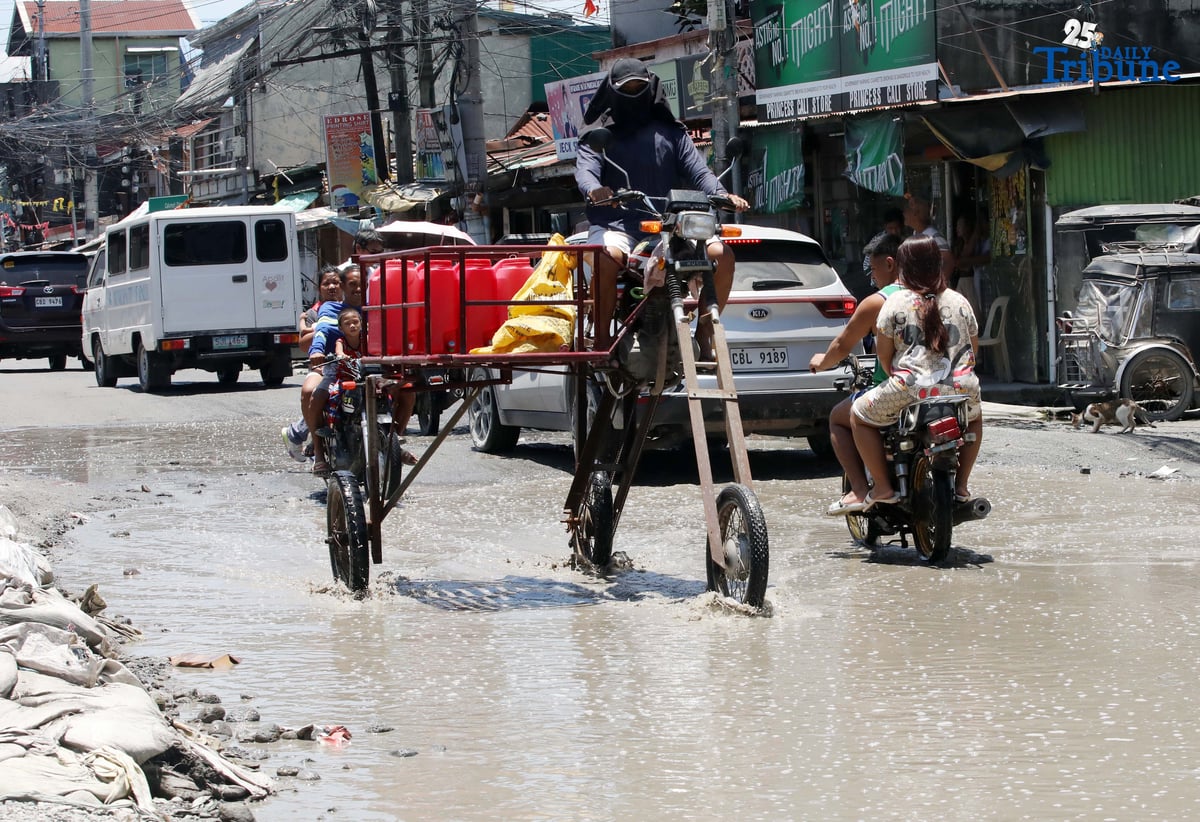 An improvised motorbike designed to navigate floods hauls water containers along a submerged portion of Apalit-Macabebe Road in Pampanga on Monday, July 4. Pampanga remains among the provinces most vulnerable to flooding.