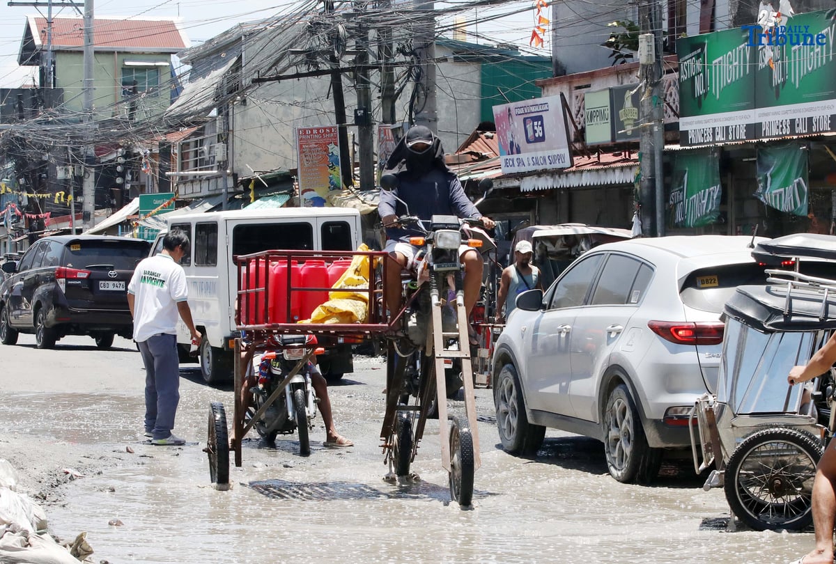 An improvised motorbike designed to navigate floods hauls water containers along a submerged portion of Apalit-Macabebe Road in Pampanga on Monday, July 4. Pampanga remains among the provinces most vulnerable to flooding.