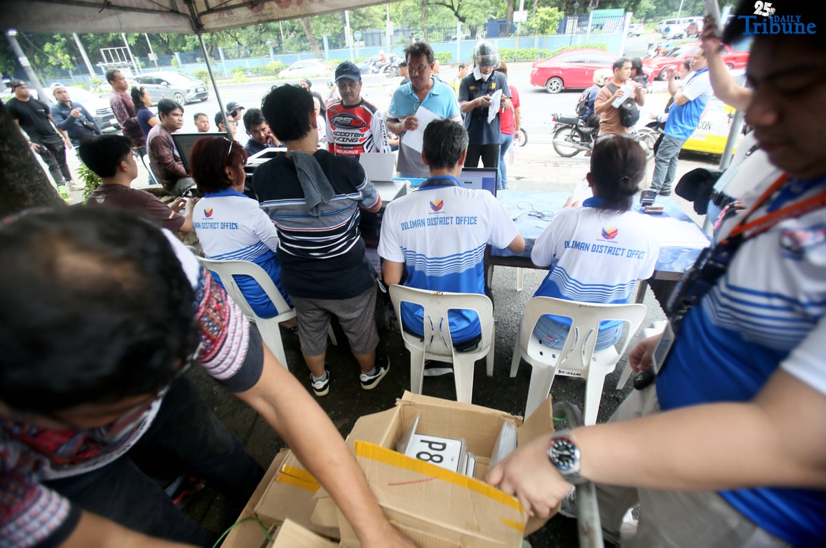 The Land Transportation Office Law Enforcement Unit assists motorcycle owners queuing for the LTO Palit Plaka program at the LTO main office along East Avenue in Quezon City on Saturday. The nationwide plate distribution program aims to address the backlog and ensure motorists comply with registration requirements.
