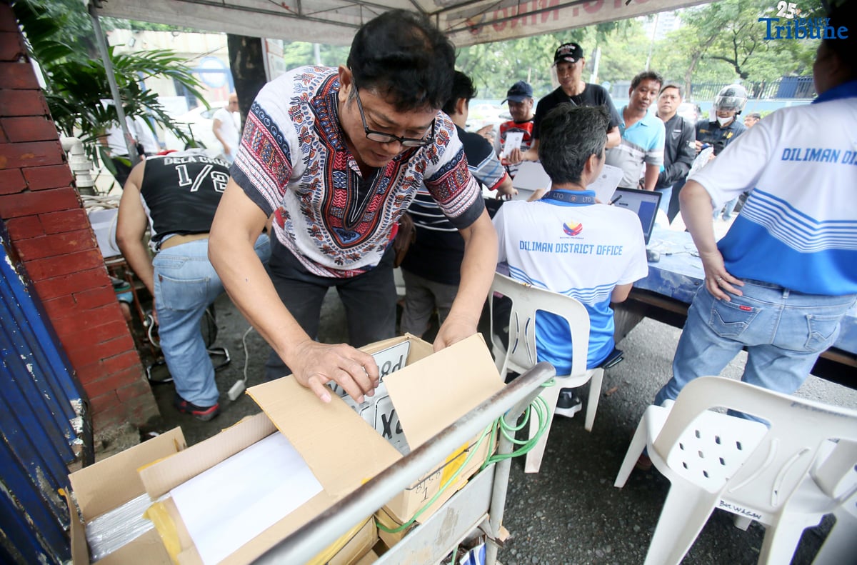 The Land Transportation Office Law Enforcement Unit assists motorcycle owners queuing for the LTO Palit Plaka program at the LTO main office along East Avenue in Quezon City on Saturday. The nationwide plate distribution program aims to address the backlog and ensure motorists comply with registration requirements.