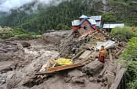 A woman looks on as she stands near a damaged house at the site of a flashflood at a village in Kishtwar district on August 15, 2025. Indian rescuers pulled bodies from mud and rubble August 15 after the latest deadly flood to crash through a Himalayan village killed at least 60 people and washed away dozens more.