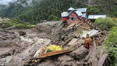 A woman looks on as she stands near a damaged house at the site of a flashflood at a village in Kishtwar district on August 15, 2025. Indian rescuers pulled bodies from mud and rubble August 15 after the latest deadly flood to crash through a Himalayan village killed at least 60 people and washed away dozens more.