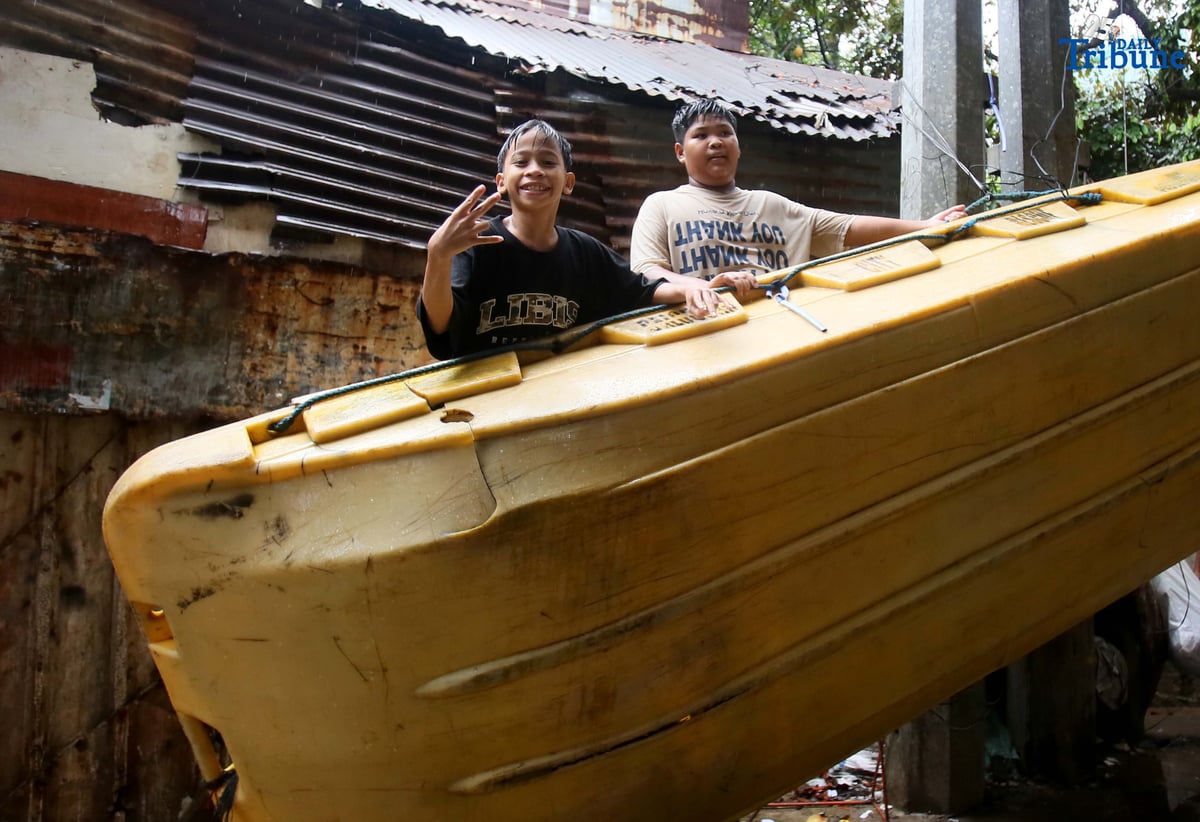 Children play on a plastic rescue boat tied near a court in Barangay 160, Caloocan City, enjoying the rain on Saturday.