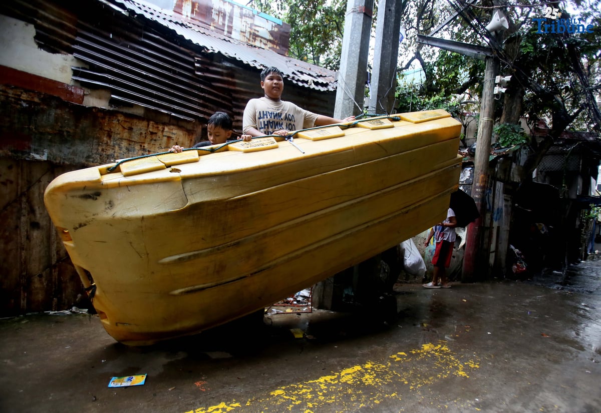 Children play on a plastic rescue boat tied near a court in Barangay 160, Caloocan City, enjoying the rain on Saturday.