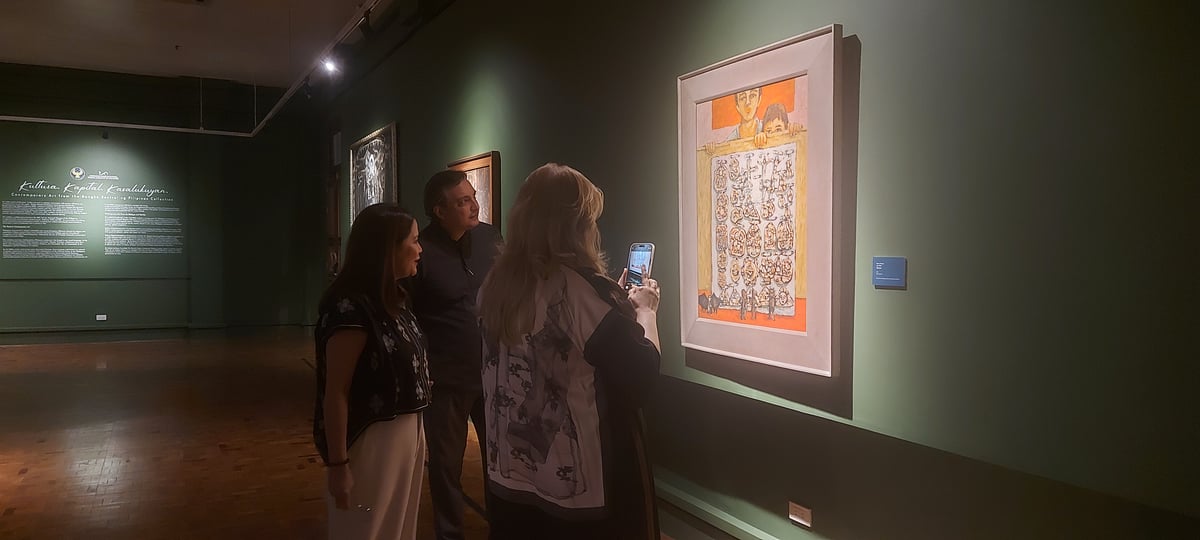 National Museum director Jeremy Barnes and BSP Deputy Governor Bernadette Romulo-Puyat looking at Mario Parial’s 1976 painting ‘Quiapo.’