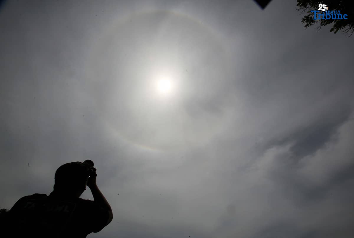 A photographer captures a visible sun halo in Quezon City on Monday. The atmospheric phenomenon occurs when sunlight refracts and reflects off tiny ice crystals suspended in high-altitude cirrus clouds.