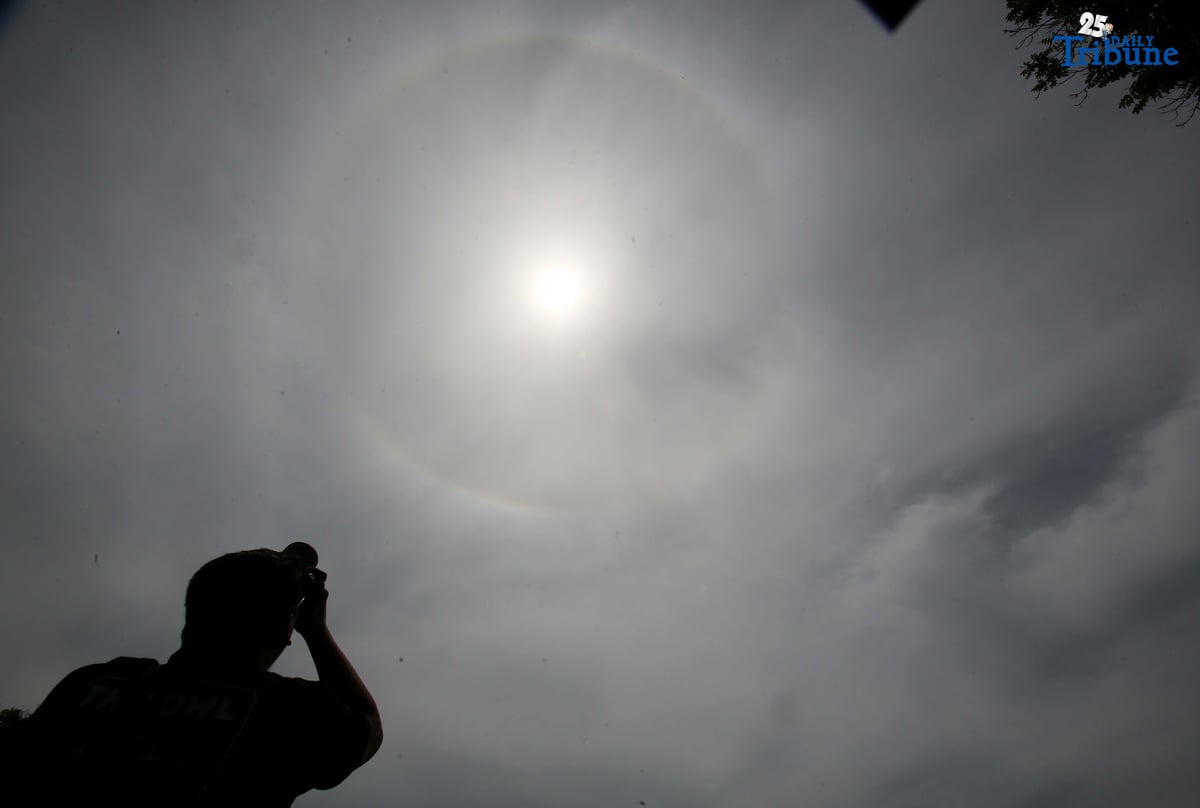 A photographer captures a visible sun halo in Quezon City on Monday. The atmospheric phenomenon occurs when sunlight refracts and reflects off tiny ice crystals suspended in high-altitude cirrus clouds.