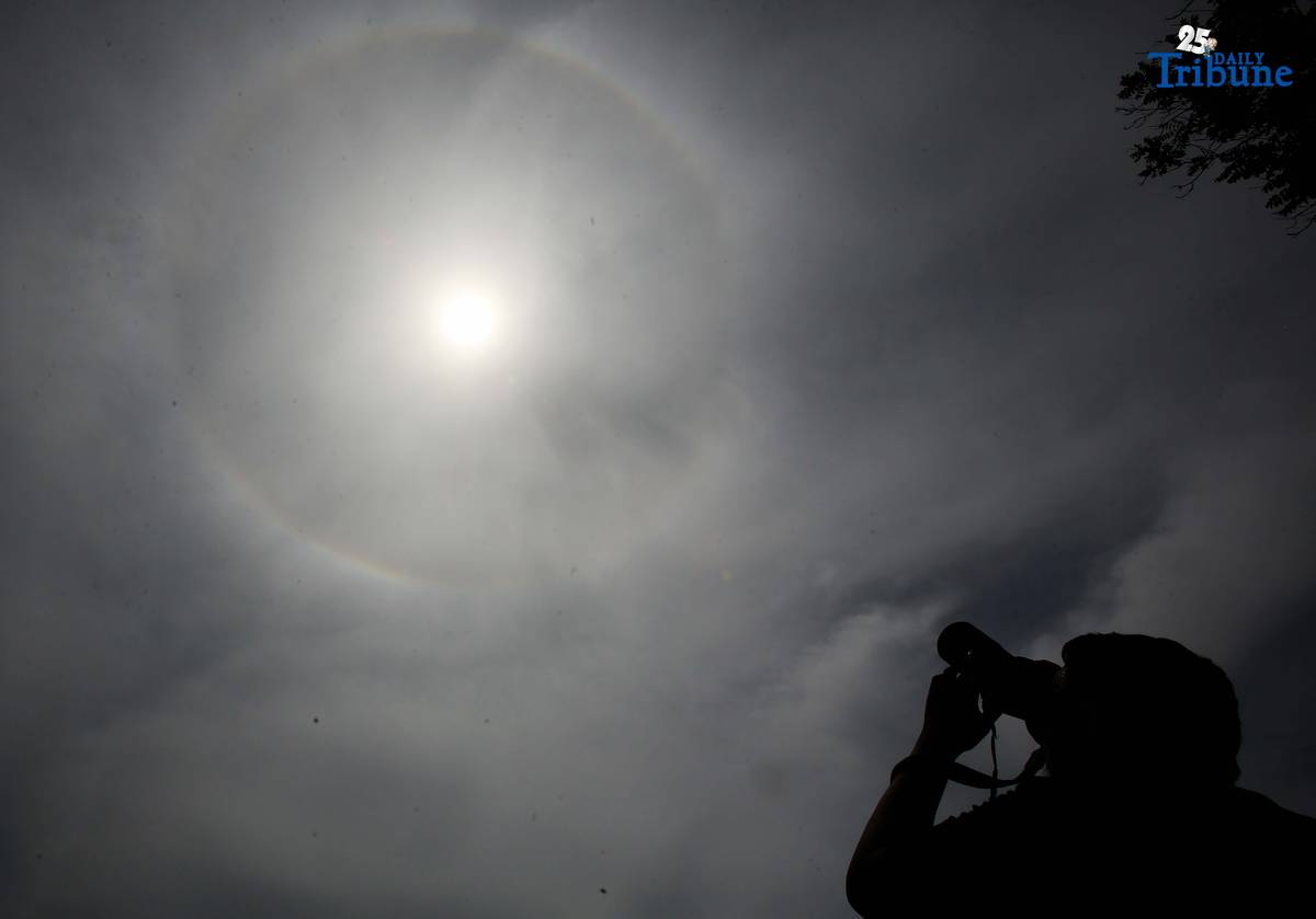 A photographer captures a visible sun halo in Quezon City on Monday. The atmospheric phenomenon occurs when sunlight refracts and reflects off tiny ice crystals suspended in high-altitude cirrus clouds.